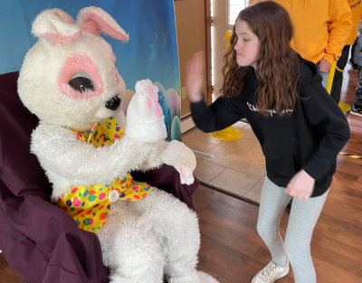Tobyn Smith, 9, of Lakeville gives the Easter Bunny a high five. She said she enjoyed the day because “it’s fun to find candy.’’
