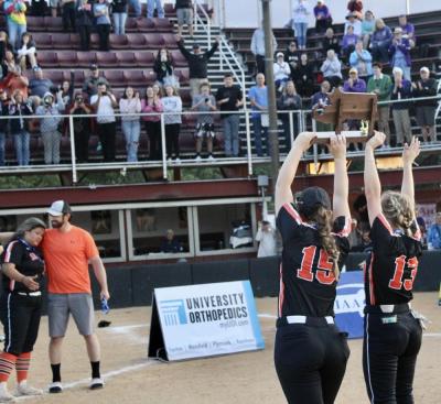 After the Middleboro High School softball team wins the state championship, Alex Welch (15) and Cassidy Machado (13) hold the trophy aloft. Photo by Brooke Chandler