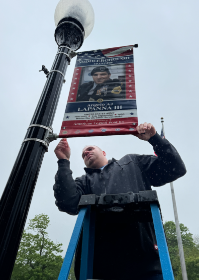 Select Board Chair Mark Germain places the banner that depicts his friend, Middleboro Police Lt. A.J. Lapanna. Photo source: Mark Germain