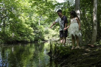 Khayron Martins-Sella, 8, and Helena Foster, 6, point to where they have seen a fish in the river at the Nemasket Herring Run Park on Saturday, June 21.