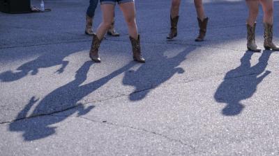 Line dancers cast a shadow onto the parking lot. An organizer led the crowd through the line-dancing steps as country music set the pace.