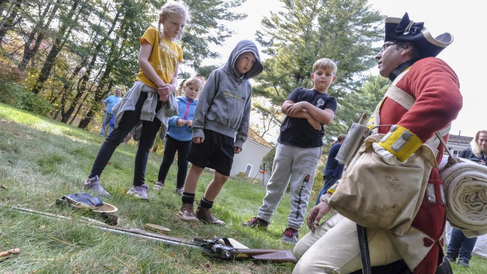 Reenactor Kyle Dunbar, right, unpacks his bedroll to show while kids — including Luke Surdis, 8, second from right — listen as Dunbar shares the unique items soldiers carried to survive on a daily basis. NONE