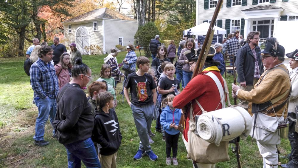 Attendees gather for a closer look at reenactors and the items they carry after a military drill. NONE