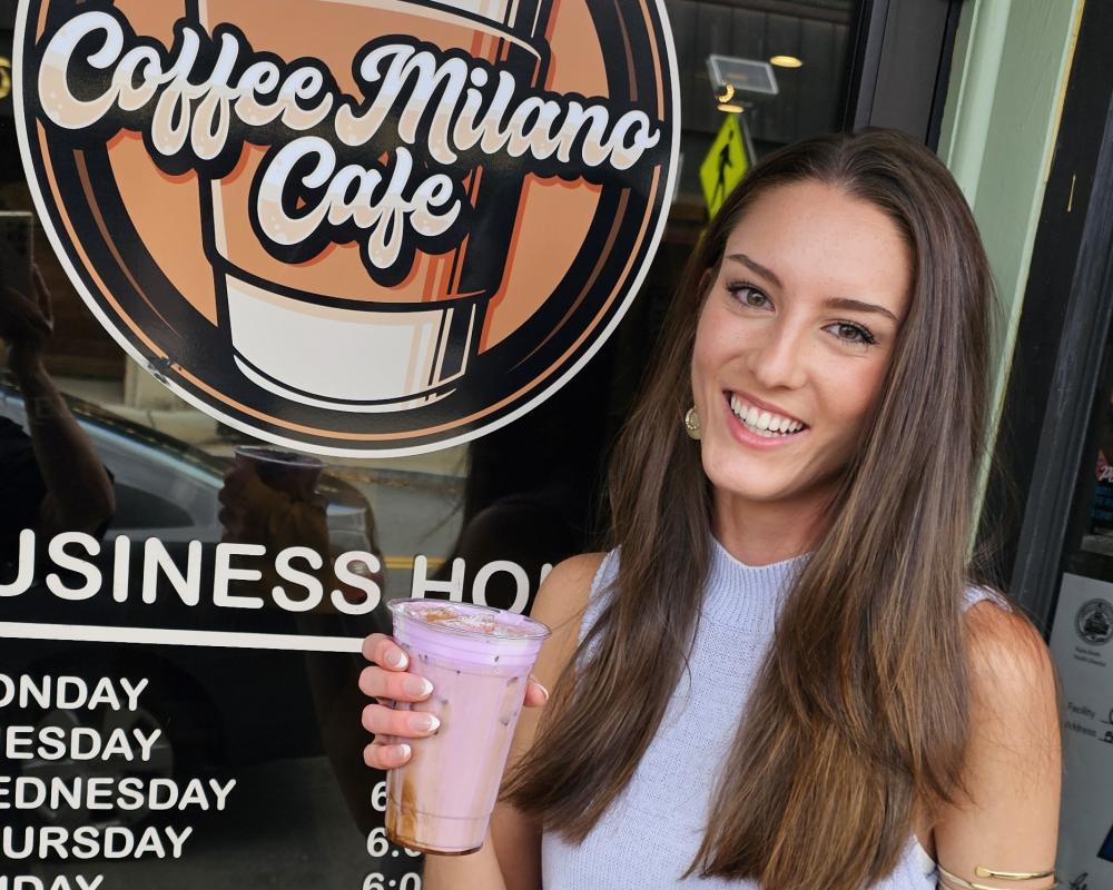 Hope Anderson stands outside Coffee Milano Cafe holding a purple cold brew. Photo source: Lorna Brunelle Hope Anderson stands outside Coffee Milano Cafe holding a purple cold brew.