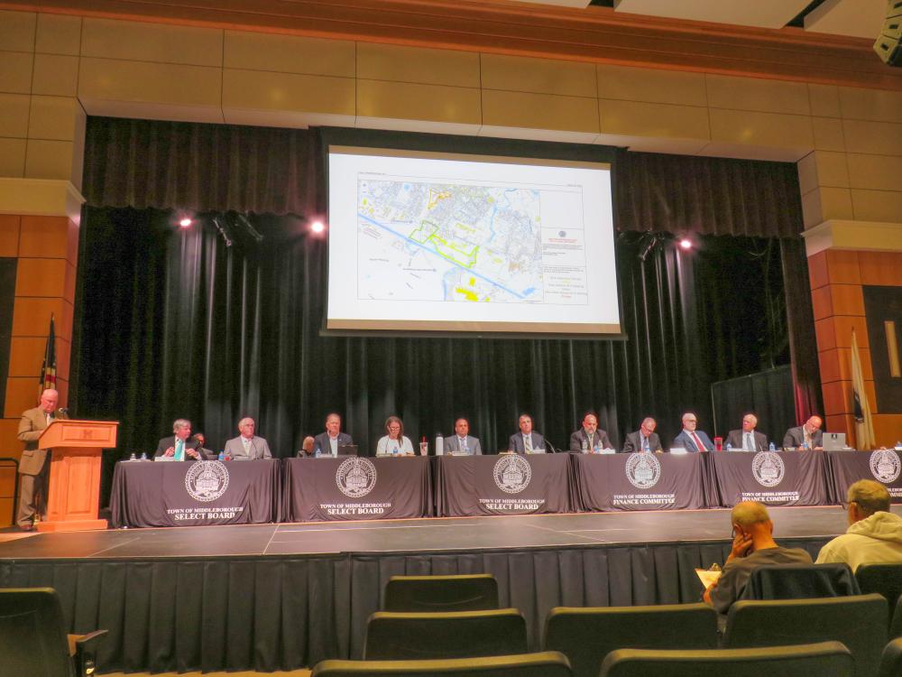 The meeting moderator, Select Board members and Finance Committee members on stage during the meeting. The meeting moderator, Select Board members and Finance Committee members on stage during the meeting.