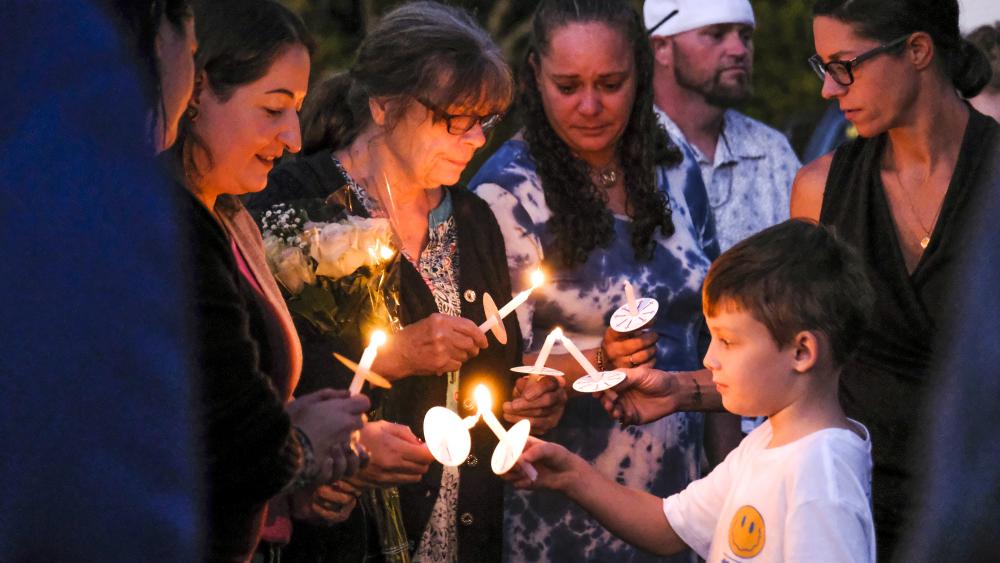 Amy Nadolny's son, Joshua Veary, 7, passes a flame between candles of family members and longtime friends during the vigil for Nadolny, Saturday, Oct. 4. Photos by Sam Tucker NONE