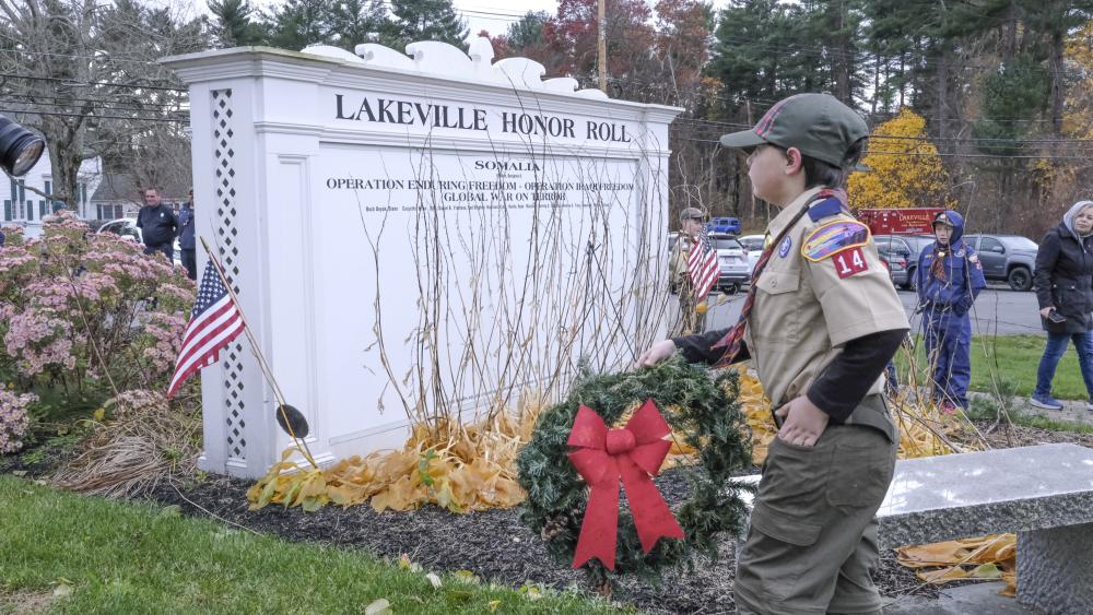 A Cub Scout walks a wreath to the Honor Roll memorial.