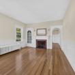 Unit 1 living room with a brick fireplace, wainscoting and an arched doorway at 370 Maple Street, New Bedford