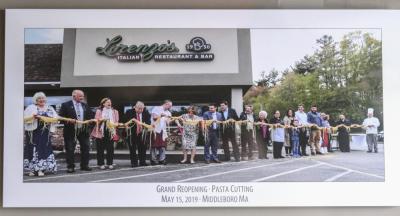 Owners and staff of Lorenzo’s Restaurant and Bar hold a large strand of pasta during a ribbon cutting event that commemorated the grand reopening in 2019.