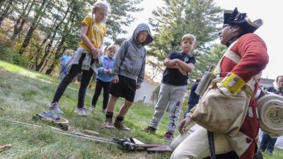 Reenactor Kyle Dunbar, right, unpacks his bedroll to show while kids — including Luke Surdis, 8, second from right — listen as Dunbar shares the unique items soldiers carried to survive on a daily basis. NONE