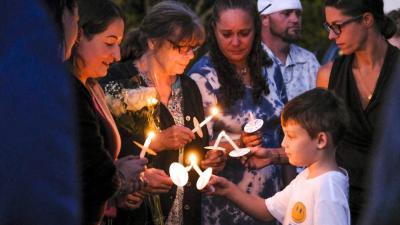 Amy Nadolny's son, Joshua Veary, 7, passes a flame between candles of family members and longtime friends during the vigil for Nadolny, Saturday, Oct. 4. Photos by Sam Tucker NONE