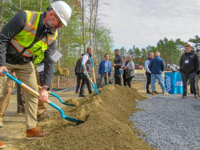 One of the project contractors shovels dirt at the ceremony. 