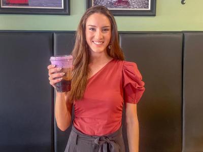 Hope Anderson poses at Coffee Milano with her purple drink for Prematurity Awareness Month. Photo by Grace Roche