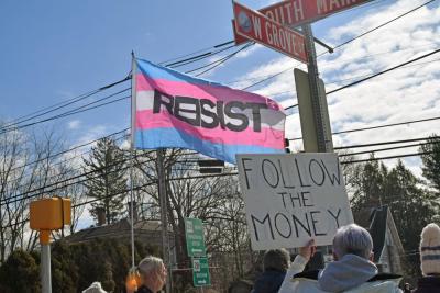 A protester waves the trans flag demanding resistance.