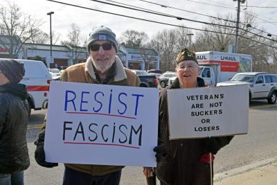 Two protestors show their signs that show their resistance to fascism and support for veterans.