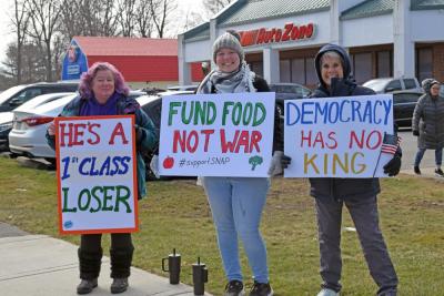 Three protesters show their signs. 