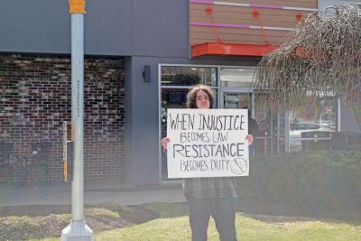 A young man shows his sign to passing cars.