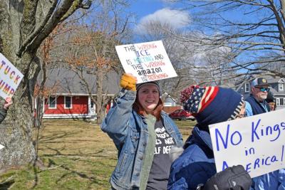 A woman holds a sign commenting on current politics and global change.