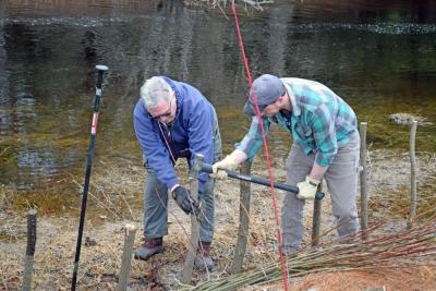 Volunteers work to hammer the posts into the ground.