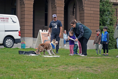 A mother helps her daughter throw a frisbee for Chaos. 