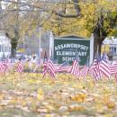 American flags flutter in the wind in front of the Assawompset Elementary School. Photo by Sam Tucker