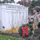 A Cub Scout walks a wreath to the Honor Roll memorial.