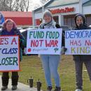 Three protesters show their signs. 