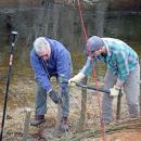 Volunteers work to hammer the posts into the ground.