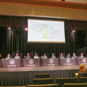 The meeting moderator, Select Board members and Finance Committee members on stage during the meeting. 