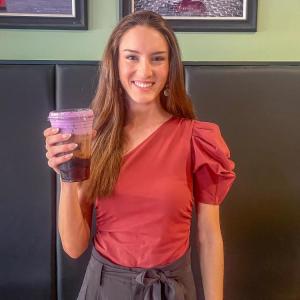 Hope Anderson poses at Coffee Milano with her purple drink for Prematurity Awareness Month. Photo by Grace Roche