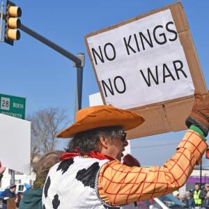 A protester dressed as Woody protests kings and wars.