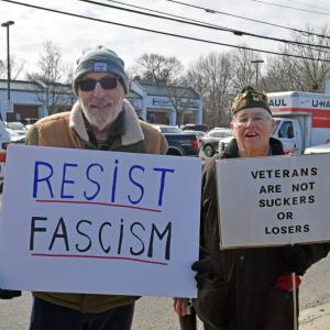 Two protestors show their signs that show their resistance to fascism and support for veterans.