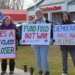 Three protesters show their signs. 