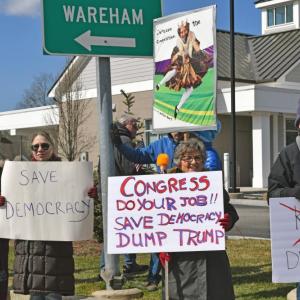 Signs calling for democracy over kings.