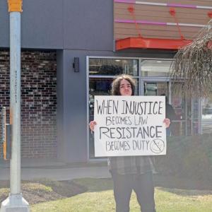 A young man shows his sign to passing cars.