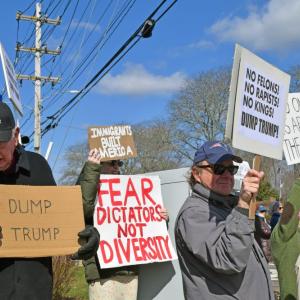 Protesters stand at the corner of the intersection. 