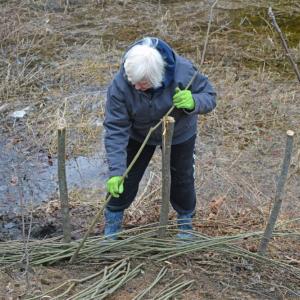 A volunteers weaves the whips.