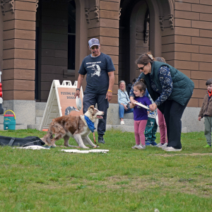 A mother helps her daughter throw a frisbee for Chaos. 